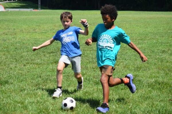 Two boys playing soccer on grassy field