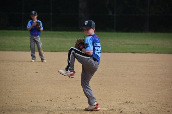 Youth pitcher winding up on baseball infield
