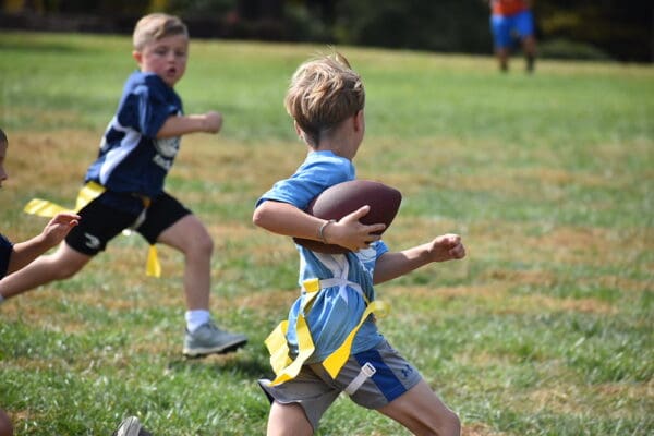 Young boy running with football in flag game