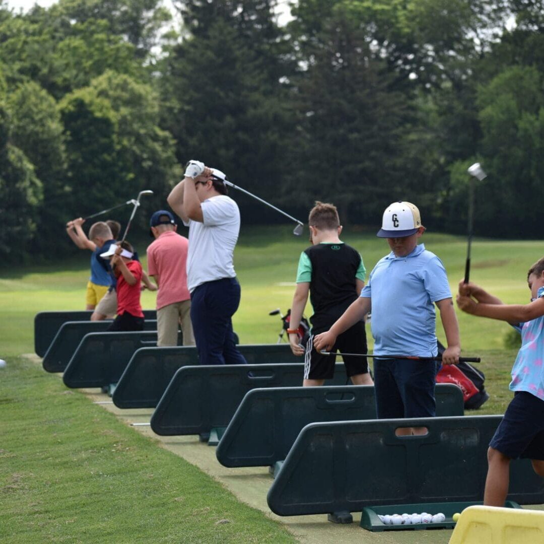 Youth golfers practicing swings at driving range